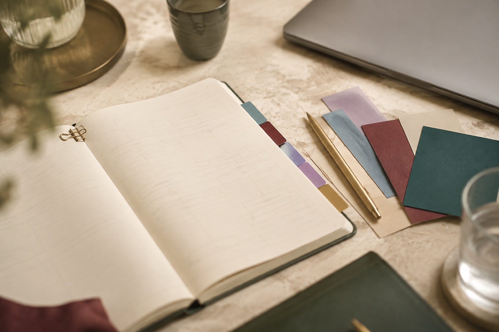 Soft-focus editorial workspace with a notebook, process cards and coloured tabs